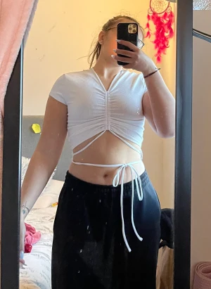 Vit H&M topp - Säljer min vita H&M topp med snören att knyta runt midjan som aldrig kommer till användning. Bra skick bara provats för bilden. 