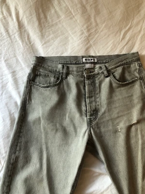 HOPE relaxed bootcut jeans - Grå jeans från HOPE i strl 32. Bra skick endast en bältesögla är lös nedtill men kan sys ganska enkelt.   Midja 44,5 cm, innerbenslängd 80, bredd på slutet av benet 24 cm. 