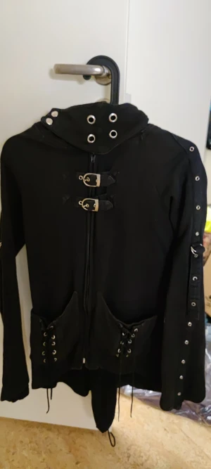 Poizen Industries Gothic Punk Jacka/Tröja Dam Stl L - Säljer en gammal jacka från märket Poizen Industries,  i Stl L, men känns mer som en M tycker jag.   Den har en dold liten ficka på armbågen. Går att knyta om snörningen på ryggen.  Riktigt snygg jacka! 