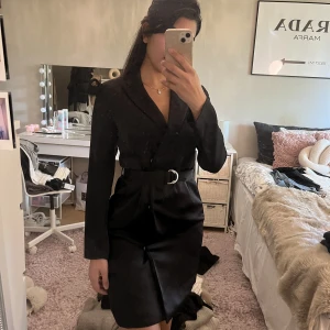 Svart satin klänning - En svart satinklänning med skärp, köpt från h&m. Använd endast vid ett tillfälle. Jätte fin för festliga tillfällen. Som ny.