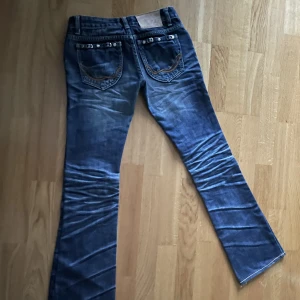 Jeans Kore Charm - Jeans märke Kore Charm med fina detalje bak o fram på fickor. Lite utsvängda nedtill, väldigt lågmidjade!! Ej stretch i tyget. Smala i låren och man får vara väldigt skinny i benen för att passa.  Typ strl 21-23 i jeans. Längd innerben 78cm, 66cm midja.