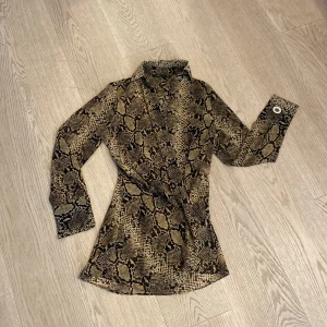 Genomskinlig topp  - Lång med djupare v-ringning som går hela vägen ner och är knuten längst ned. Genomskinligt material. 