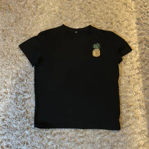 Svart t shirt  - Svart t shirt med liten söt annans på🍍. Använd få gånger, nästan nyskick.