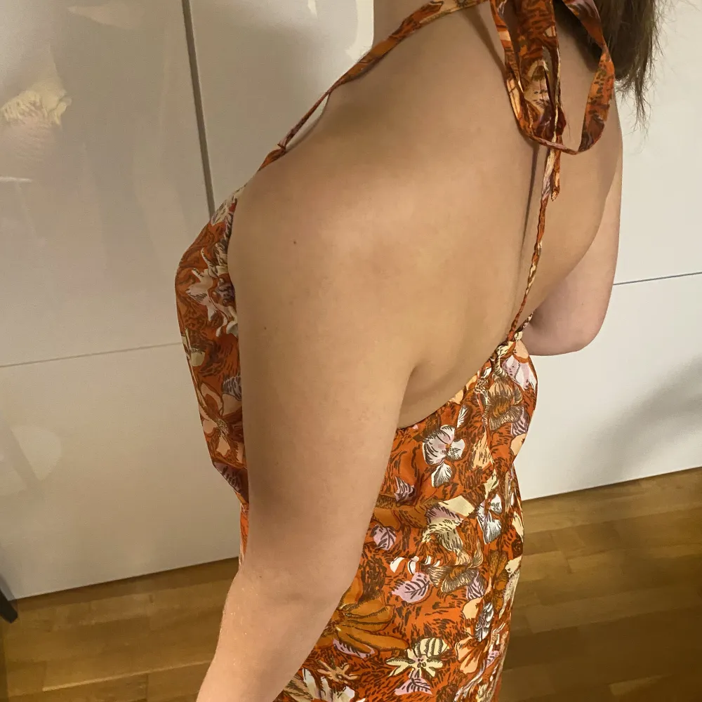 Orange klänning med öppen rygg och blommigt mönster! Funkar för sommar men även höst pga färgen🦀🪐✨. Klänningar.