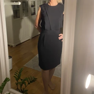 Filippa K klänning - Svart klänning med underkjol. Klänningen har mycket detaljer på överkroppen som syns på bilden. Öppen i ryggen. Fint skick.