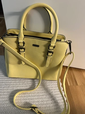 Gul väska/ axelremsväska - Säljer min fina gula väska/ axelremsväska. Finns så bra förvaring i den med flera fack! Nyskick då den knappt är använd. 140💜 från märket dondonna 