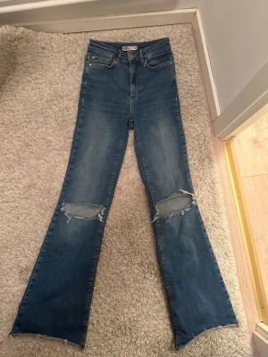 Boot cut jeans  - Bootcut jeans med hål vid knäna Storlek xs. Stretch. 