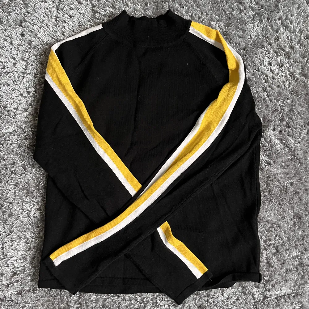 Tunn svart stickad tröja med gula och vita ränder på armarna🤍 Från H&M Storlek S Använd 2-3 gånger . Tröjor & Koftor.