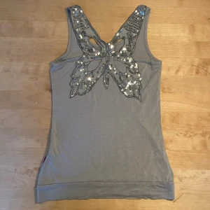 fint linne med paljetter  - supergulligt linne men paljetter som formar en fjäril på ryggen! Den är i superbra skick anledningen till att jag säljer den är för att den är för liten. Färgen är ungefär grå/blå. Det är bara att ställa frågor och är nästan alltid öppen för prisförslag!💗