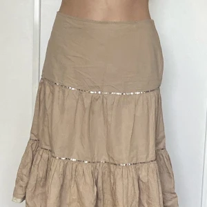 Beige kjol med paljetter - Jättefin kjol som går precis över knäna :)  Tyvärr har dragkedjan gått sönder, men går säkert att laga!