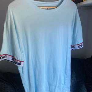 Moschino t-shirt ljusblå - En ljusblå t-shirt från Moschino, herr storlek L. Ljusblå färg. Endast använd en gång!