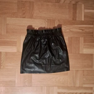 Svart fake-skinnkjol - Svart fake-skinnkjol i storlek 38. Nyskick! :)