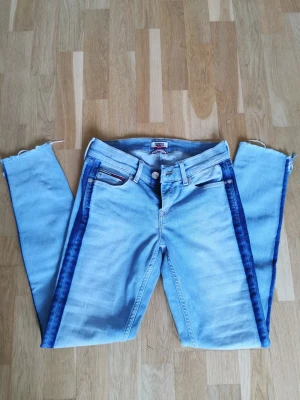 Unika jeans från Tommy Hilfiger  - Supercoola blåa jeans från Tommy Hilfiger. Designen är så unik! De är inte avklippta av mig, utan det är så de är designade. Perfekta till sommaren! ☀️