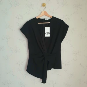 Zara svart asymmetrisk väst - ☀️FÖRST TILL KVARN☀️ En liten impulsköp av mig, så helt ny i nyskick. Zara asymetrisk svart väst med en knut detalj i fram. Superfin med en vit skjorta under. Aldrig använd med prislapp kvar.