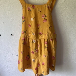 Romper - Romper orange/gul med ljus röda blommor. Är i bra skick med en fungerande drag kedja på baksidan. 