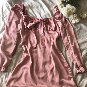 Klänning - Rosa klänning med rosettknut! Supersnygg passar till fest, middagar men även luncher och mer vardagliga tillställningar.  Hittar ingen lapp, gissar Storlek större M eller L