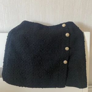 Svart kjol - Svart snygg klassisk kjol med guldknappar och en liten slits. 