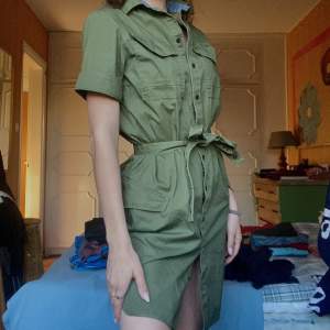 En klänning i cargostil.  Jag är 168 cm lång. Klänningen slutar straxt över knät Militärgrön Orginalpris 900