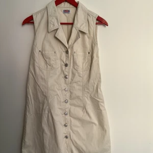 Skjortklänning  - Skjortklänning i stabilt tyg, gör att den håller formen. Jag är S/M och har trivts bra i storleken, sitter ej tajt. Storleken finns ej markerad i plagget. Finns tyg att lägga ut den ytterligare. 