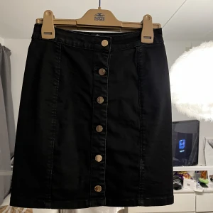 Stretchig jeanskjol - Med knappar. Finns liten fläck nere till höger som syns på bilden. Jättestretchig och sitter snyggt på rumpan. Från missguided