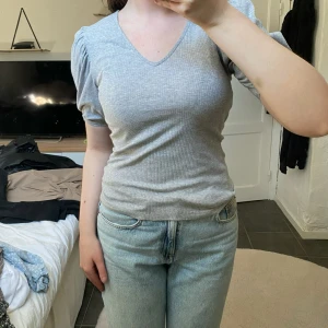 TOPP - Kortärmad topp med v-rigning och puffiga ärmar. 