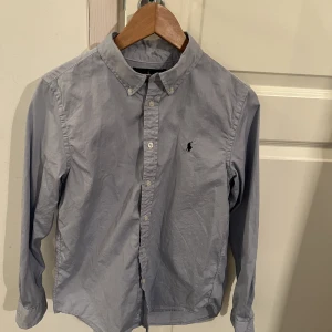 Ralph Lauren skjorta i bomull - Ralph Lauren skjorta som är i princip oanvänd eftersom att jag fick den när jag var yngre och växte ur den direkt, den är storlek 18 youth, vilket motsvarar ungefär XS-S i storlek. Som sagt är den nästan i nyskick.