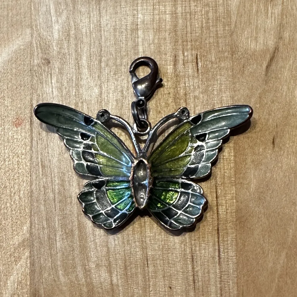Ett fint hänge med en fjäril i grön färgskala, kan användas på både halsband och nyckelring. Accessoarer.