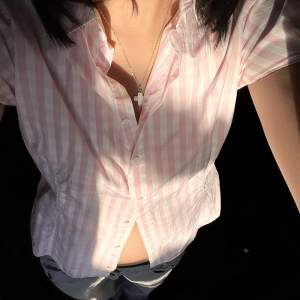 En rosa/vit randig skjorta med korta ärmar och form sydd