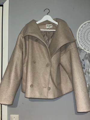 Kappa - Beige kappa ifrån NAKD. Storlek 40 kan användas oversize. Använd och har några avvikelser , knopprig och missfärgad ( se bild ) 