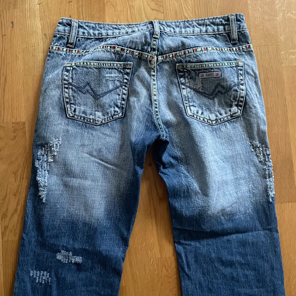 Helt fantastiska lågmidjade bootcut jeans me snygga rhinestone detaljer å slitningar. I nyskick!! Jag är 165 cm för referens. Mått: 40 cm midja tvärs över, 87 cm innerbenslängd . Jeans & Byxor.