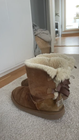 Uggs  - Säljer nu dessa bruna uggs med rosetter på baksidan. Uggsen är i sämre skick och har vattenskador därav priset. Skorna är i storlek 34, men passar mig som vanligt vis har storlek 36. Priset kan diskuteras.(Äkta uggs)