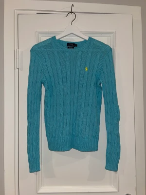 Härlig turkos kabelstickad Ralph Lauren tröja - Turkos polo Ralph lauren tröja. Tröjan är I ett mycket bra skick och har används att 2 gånger.  Den är normal i storleken. Tröjan gjord i 100% bomull och är väldigt skön att ha på sig. Den är inte urtvättad och känns väldigt mjuk. 