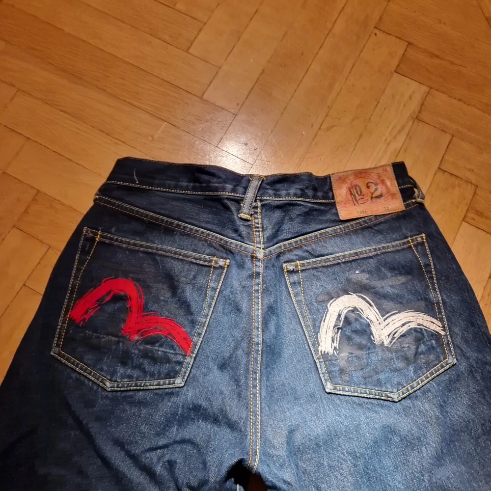 90-tal Evisu-jeans no.2 med seagull-tryck i rött och vitt. Lite baggy med lite smalare vid foten så att byxorna lägger sig på skorna. Väldigt bra skick, bara lite nött längst ner på ena benet. Storlek 32. . Jeans & Byxor.