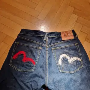 90-tal Evisu-jeans no.2 med seagull-tryck i rött och vitt. Lite baggy med lite smalare vid foten så att byxorna lägger sig på skorna. Väldigt bra skick, bara lite nött längst ner på ena benet. Storlek 32. 