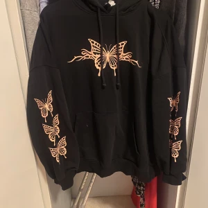 Svart hoddie - svart hoddie från HM med fjärils detalj. Varm och skön. Använd tröja men i gott skick (inga defekter) strl M men är oversized