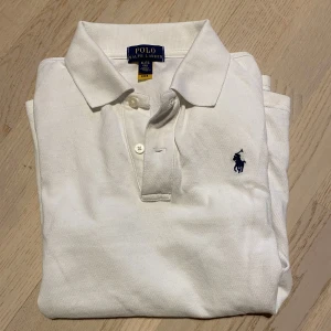 Vit Ralph lauren pike - Vi säljer en vit  Ralph lauren pike för ett bra pris även dess bra skick. Det är inga hål, fläckar eller andra defekter. Priset kan diskuteras.OPS tröjan är lite liten i storleken så de står 16 (176cm) men jag skulle säga att den passar dem runt 168-174cm