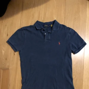 POLO RALPH LAUREN PIKÉ - Äkta Ralph Lauren piké i bra skick, inga hål eller tecken på slitage. Färgen är i blå, lite tvättad färg. Pris kan diskuteras vid snabb affär.