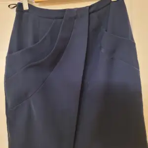 Kort asymmetrisk kjol i mörkblått. Vackert sydd med fickor.