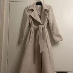 Beige kappa - Superfin och tjock kappa med skärp, använd 2 gånger så i nyskick. Storlek 36 