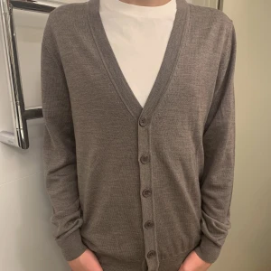 Cardigan (100 % merino)  - Helt ny stickad cardigan i 100 % merinowool från Magasin Du Nord, Alla tags kvar, för tröjan är sprillans ny som sagt. Priset på tröjan på Magasin Du Nords hemsida är 1500 kr och vi säljer för 859 kr (båda helt nya). Skickar gärna fler bilder, hör av er!