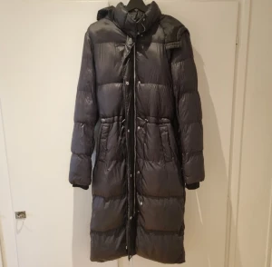 Lång pufferjacka  - Snygg vaderad vinterjacka som är använd en månad förra året så väldigt bra skick! Har dragsko för att framhäva midjan. 
