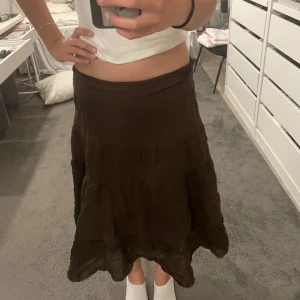 Lång brun kjol - Det är en väldigt fin lång brun kjol! Den är insyd i midjan för att den var lite stor, inte använd många gånger, volang. Kan byta pris