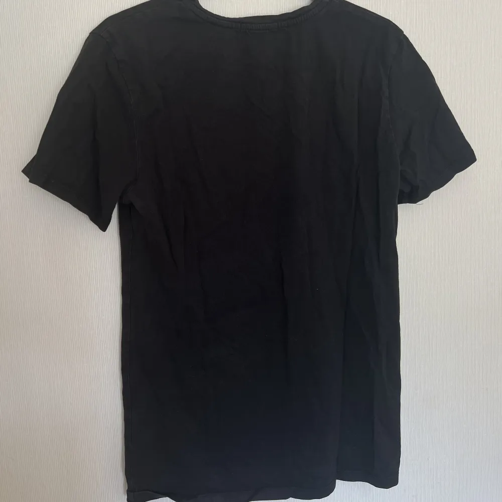En svart T-shirt med tryck i storlek XS från Nakd. Relativt använd och trycket är lite halvt slitet (se ovan). Relativt figurnära material och har tyvärr växt ut. Köpt för ca 300kr.. T-shirts.