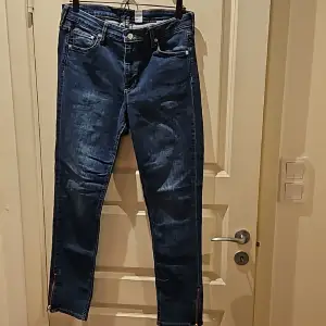 Ett par blåa normalmidjade jeans i stl 32. Jeansen är av modellen skinny ankel från H&M och har sragkedja nedtill benslut (se bild 2). Använda och är i bra skick.