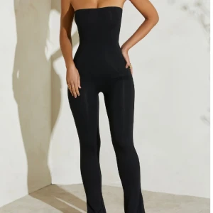Jumpsuit från Oh Polly  - Säljer en svart bandeau jumpsuit med slits i benen i svart från Oh Polly i S. Endast använd en gång och är i nyskick. Nypriset är 750 kr.