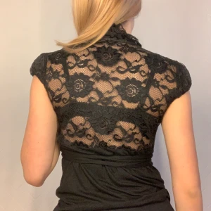 Svart spetts tröja - Svart spetts tröja med band runt midjan man kan knyta hur man vill. öppen rygg me spetts detaljer