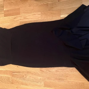 Klänning, volanger  - Svart figursydd klänning från Boohoo med volanger längst ned. Superfin och fladdrig, i storlek 38. 