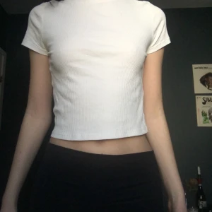 Vit tshirt  - En fin vit tshirt i lite ribbat material från H&M, divided. Bra basplagg som passar till det mesta. En liten defekt uppe till vänster på tröjan, en beige fläck. 