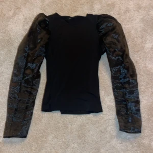 Svart topp med meshärmar - Svart topp med strechigt tyg och mesh-ärmar!