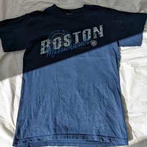 Blå tshirt köpt i Boston, stadigt bommulstyg